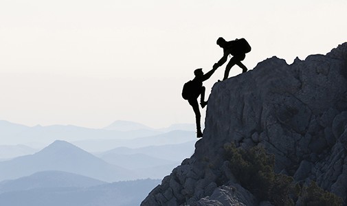 Ein Bergsteiger hilft einem anderen Bergsteiger